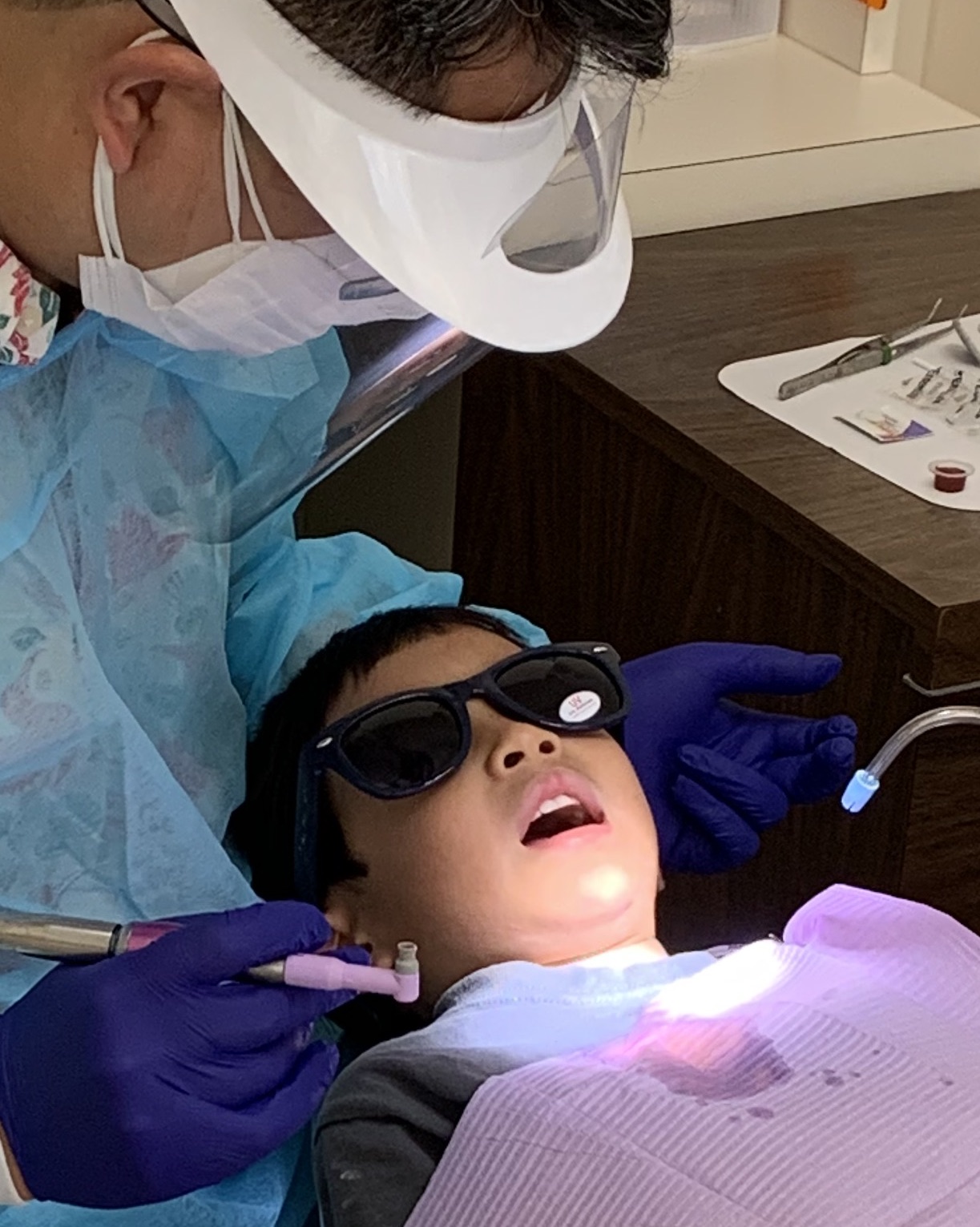 Child patient receiving dental treatment while wearing protective eyewear
